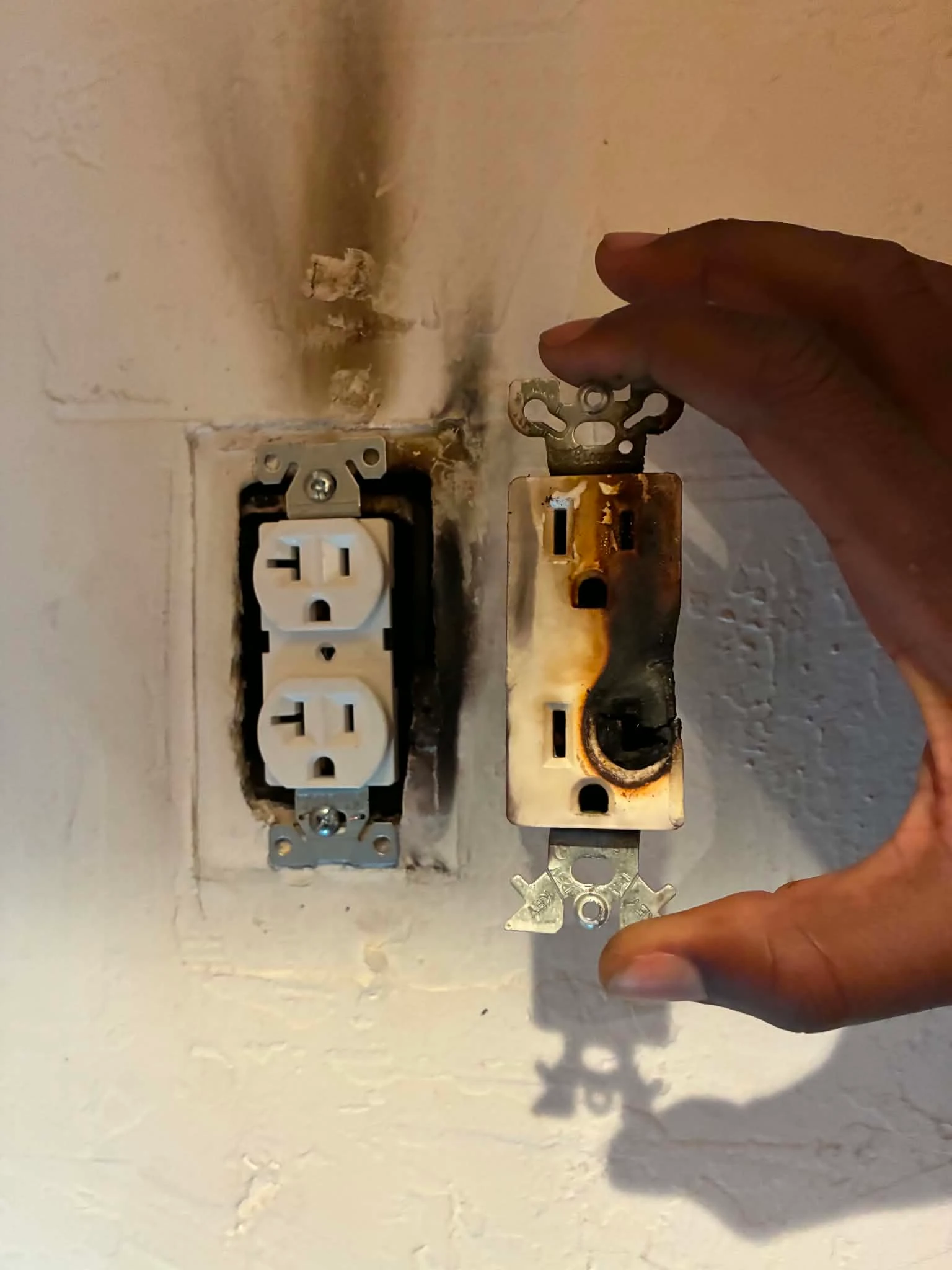 Burned electrical outlet with visible heat damage before repair